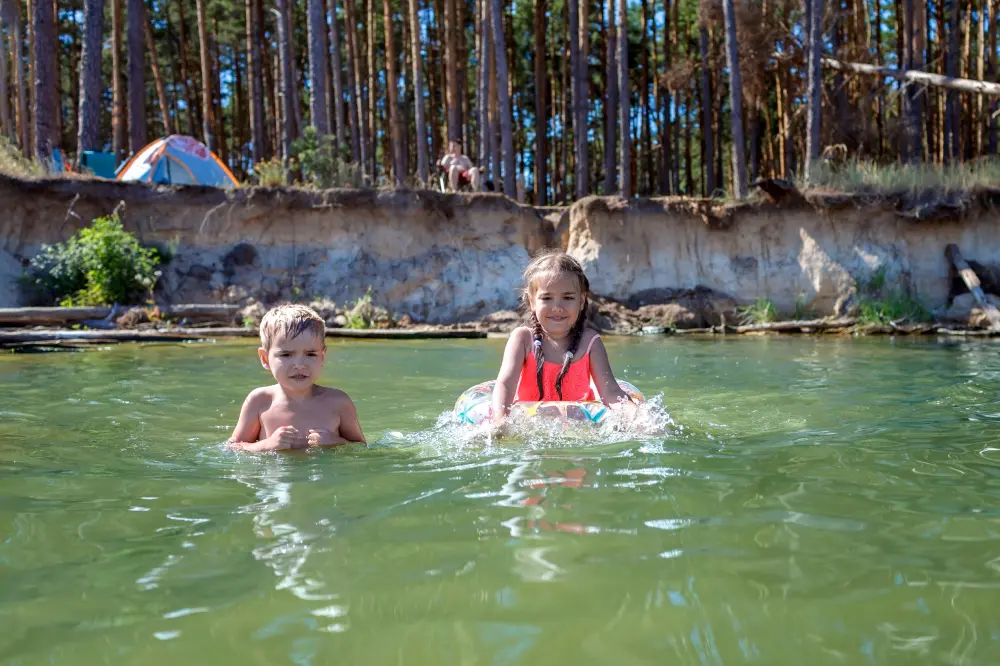 Дети купаются в лесном озере рядом с лагерем во время семейного путешествия