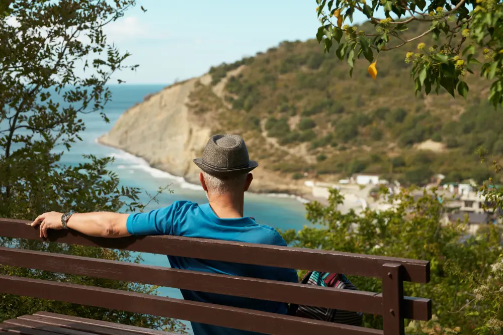 Мужчина на скамейке любуется видом на бухту