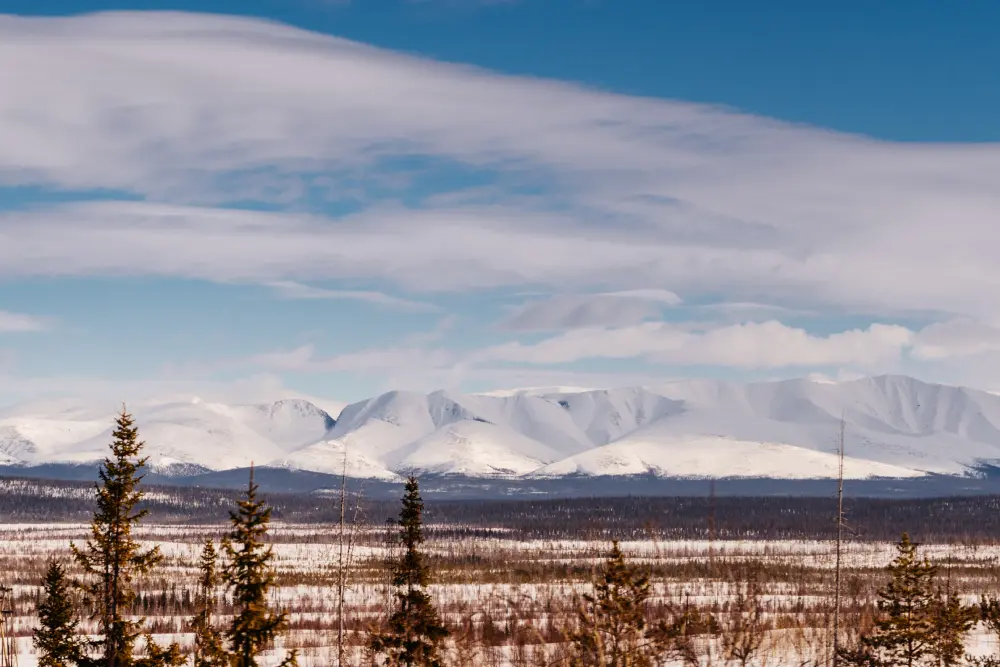 Заснеженное поле на фоне высоких зимних гор в Хибинах