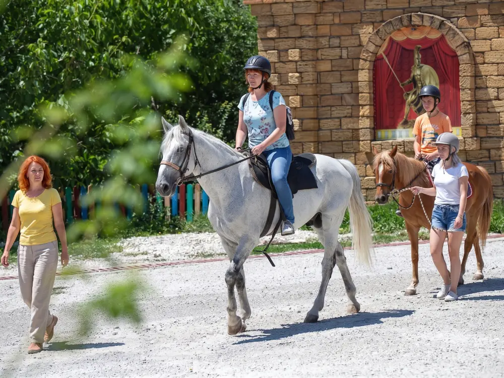 Женщина и ребёнок катаются верхом на лошадях в Культурно-туристическом комплексе «Россия» (Абрау-Дюрсо)