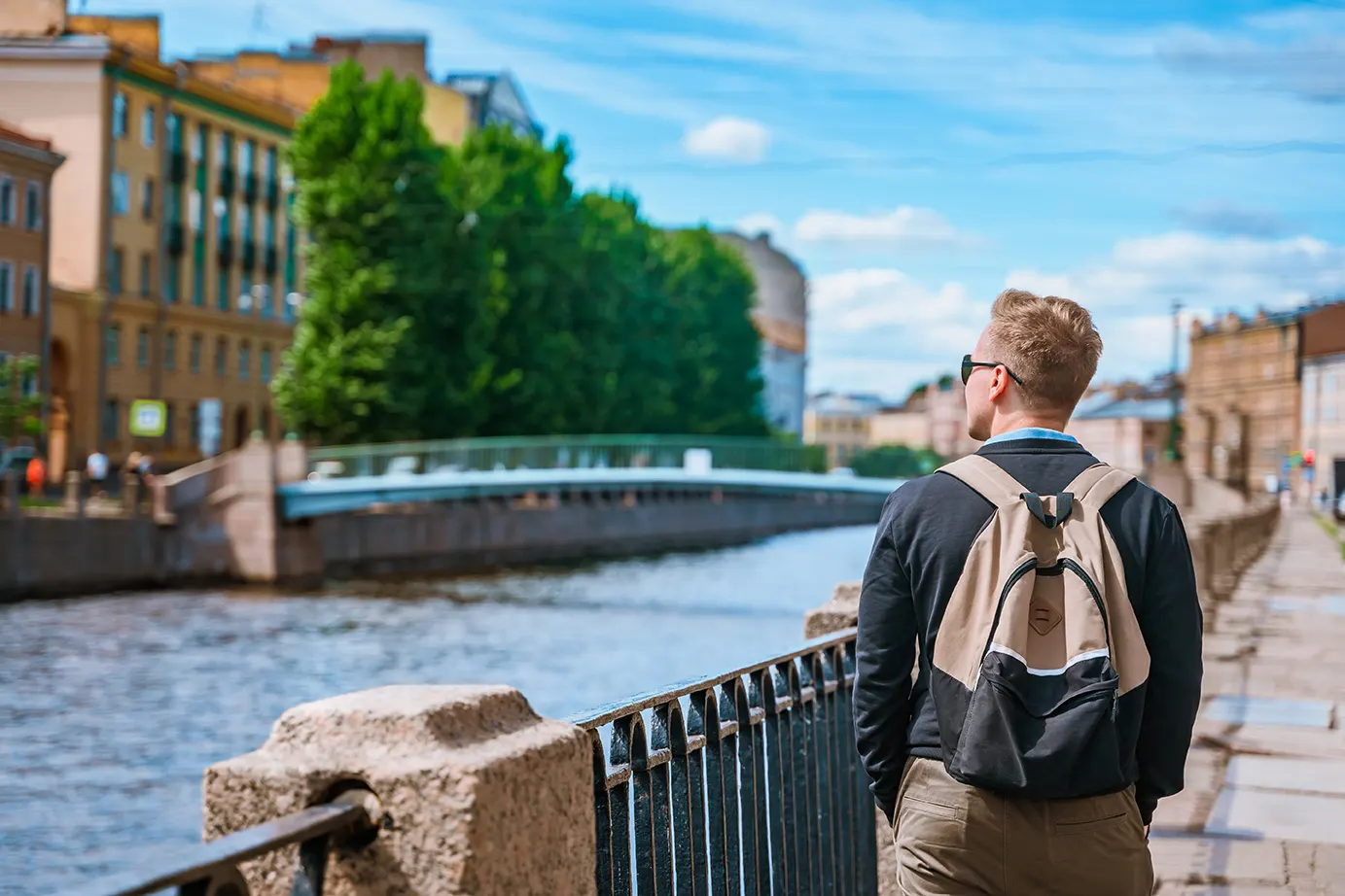 Молодой человек гуляет по набережной Санкт-Петербурга с прекрасным видом на мосты и каналы