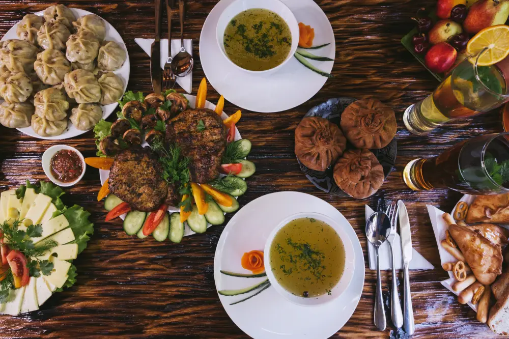 Cтол c алтайскими блюдами: буузы с мясом в тесте, мясная шурпа, пироги, овощи и зелень