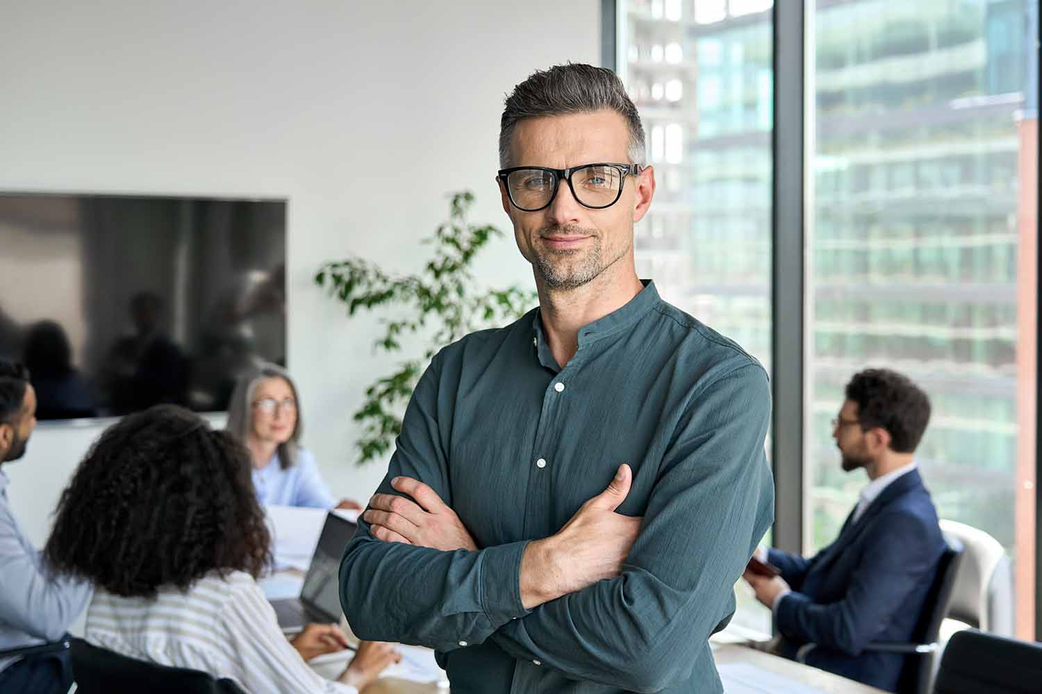 Исполнительный менеджер в очках позирует для делового портрета со сложенными руками