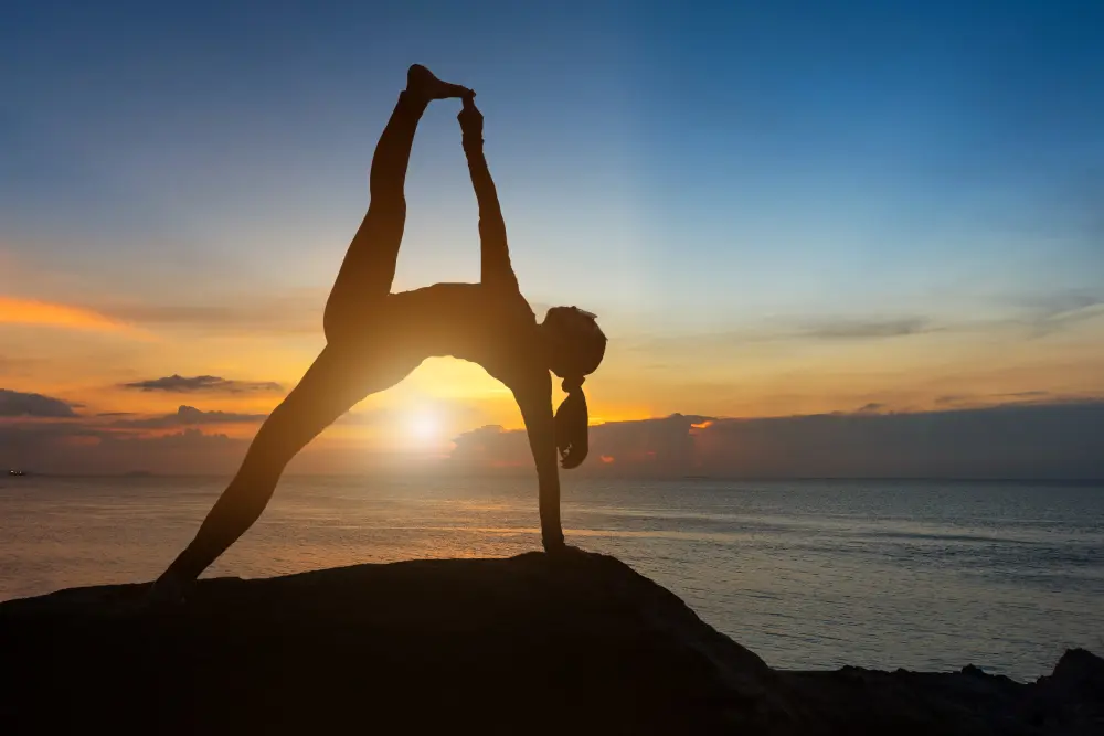 Женщина на вершине горы занимается йогой