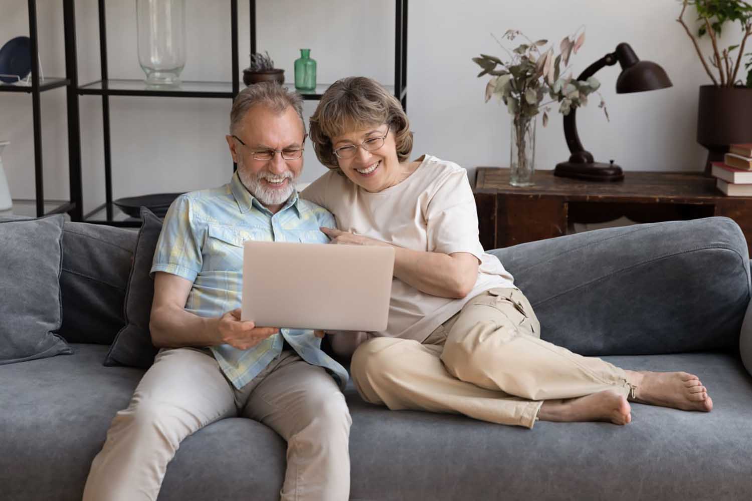 Пара среднего возраста сидит на диване у себя дома и смотрят онлайн-трансляцию