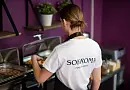Сотрудница отеля в футболке с логотипом «Sokroma» пополняет блюда на шведском столе